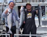 Two fishermen holding large salmon on a boat in Santa Cruz.