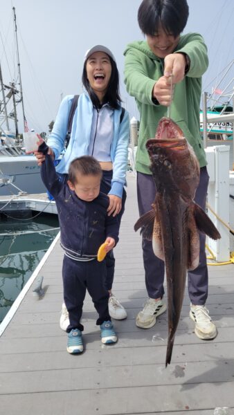 Family holding a large fish caught during a fishing trip at Santa Cruz marina.