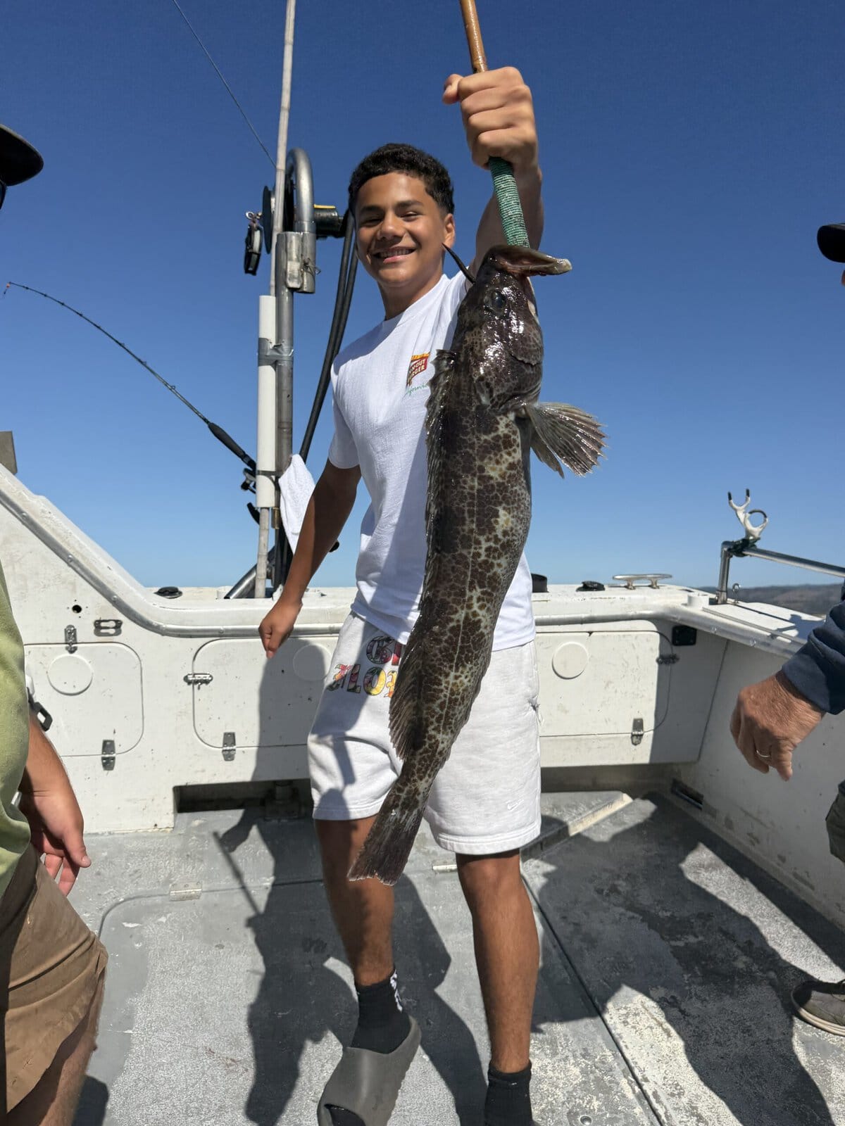Young angler with large fish on boat