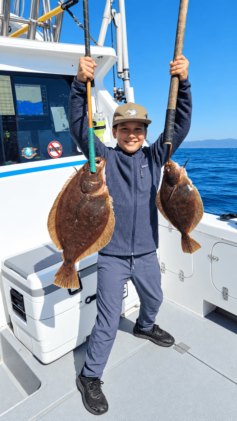 Young angler with caught fish on boat
